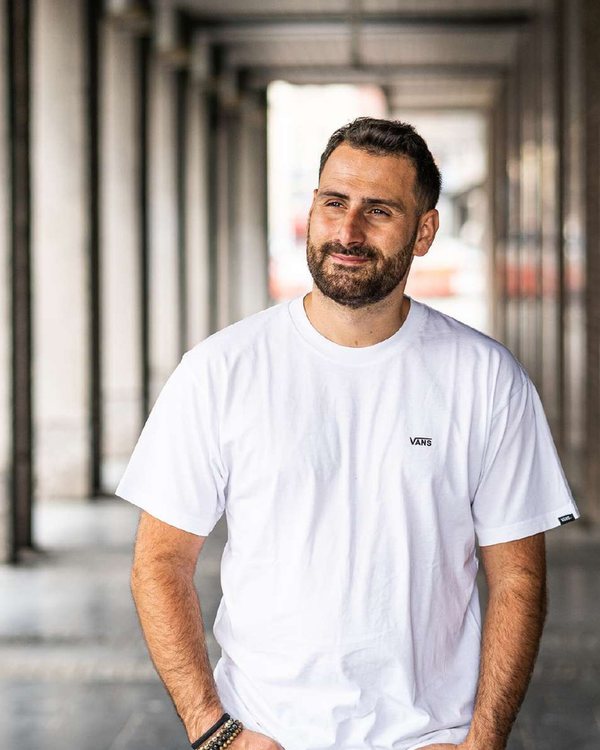 Portrait de Melfiano en t-shirt blanc sous une galerie à colonnes